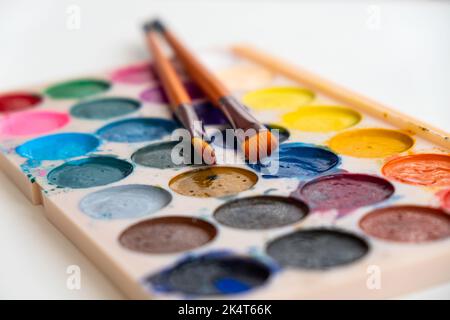 Karton mit gebrauchten Aquarellfarben und Pinsel. Stockfoto