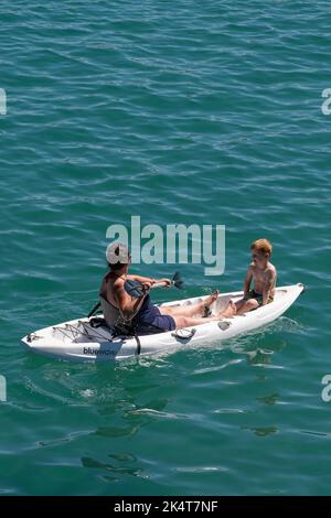 Eine Mutter und ein Kind sitzen auf einem Kajak in Newquay Bay in Cornwall in England im Vereinigten Königreich. Stockfoto