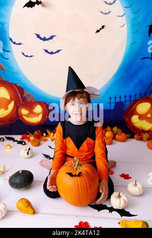 Halloween-Konzept. Lächelndes Kind mit Kürbissen auf gruseligen Halloween Hintergrund Stockfoto