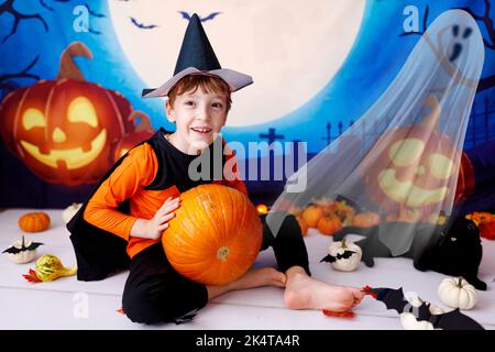 Halloween-Konzept. Lächelndes Kind mit Kürbissen auf gruseligen Halloween Hintergrund Stockfoto