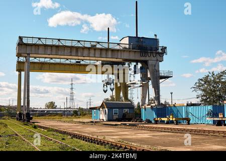 Industriekran mit Containern und Eisenbahn im Hintergrund Stockfoto