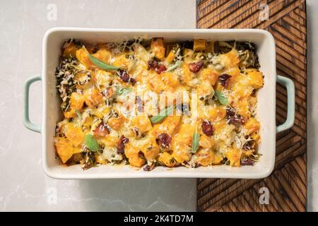 Herbstlicher Kürbisauflauf mit Lauch, Speck und Grünkohl Stockfoto