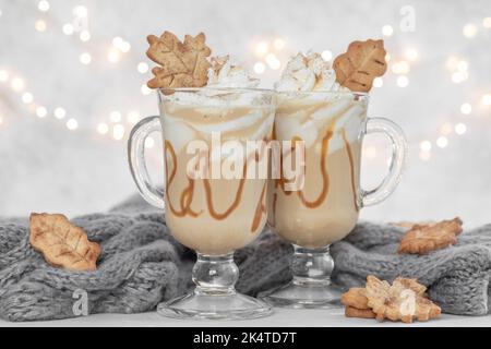 Kürbis-Gewürz-Latte in einem Glaskrug mit Karamell und Zimt mit Herbstdeko Stockfoto