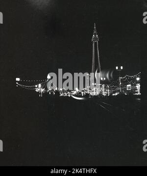 1955, historisch, bei Nacht ein Blick auf die berühmten Blackpool Illumations, einschließlich Blackpool Tower, England, Großbritannien. Die Lichter stammen aus dem vorigen Jahrhundert und sind ein jährliches Lichterfest, das an der Promenade im Badeort stattfindet. Eine Million sind Leuchten, die für die Lichtshow verwendet werden, wobei das ursprüngliche Ereignis 1879, das der Registrierung des Patents für die elektrische Glühlampe vorausging, vorausging. Stockfoto