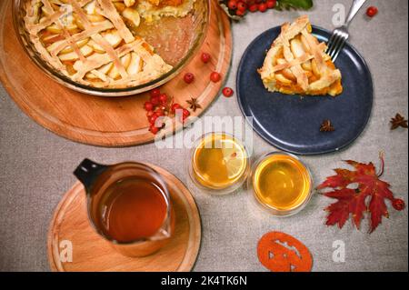 Stillleben. Hausgemachter Kürbiskuchen mit knuspriger Kruste und Tassen Tee, umgeben von Viburnum-Beeren und gefallenen Ahornblättern Stockfoto