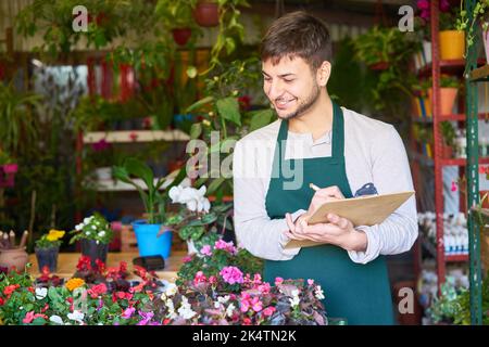 Florist mit Zwischenablage und Checkliste tun Inventar oder Qualitätskontrolle im Blumenladen Stockfoto
