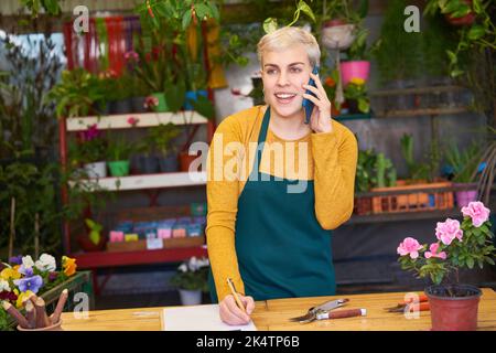 Weibliche Floristin im Blumenladen am Telefon, die Bestellung für die Lieferung als Service Stockfoto