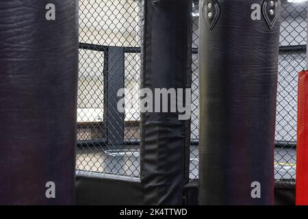 Ein achteckiger Kickboxen-Käfig mit Boxsäcken im Sportkomplex. Stockfoto