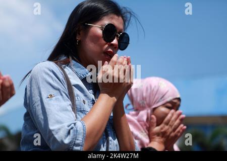 Malang, Indonesien. 4. Oktober 2022. Menschen trauern um die Opfer vor einem Eingang des Kanjuruhan-Stadions in Malang, Ost-Java, Indonesien, 4. Oktober 2022. Die indonesische Regierung hat ein unabhängiges Team eingerichtet, um die Ursache des Ansturm zu ermitteln, bei dem 125 Menschen getötet und mindestens 320 weitere verletzt wurden. Der Stampede ereignete sich am späten Samstag im Kanjuruhan Stadium in der Regentschaft Malang, nachdem der Verein Arema Malang in einem indonesischen Fußballspiel gegen Persebaya Surabaya verloren hatte. Quelle: Bayu Novanta/Xinhua/Alamy Live News Stockfoto