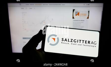 Person, die Mobiltelefon mit Logo des deutschen Stahlunternehmens Salzgitter AG auf dem Bildschirm vor der Business-Webseite hält. Konzentrieren Sie sich auf die Telefonanzeige. Stockfoto