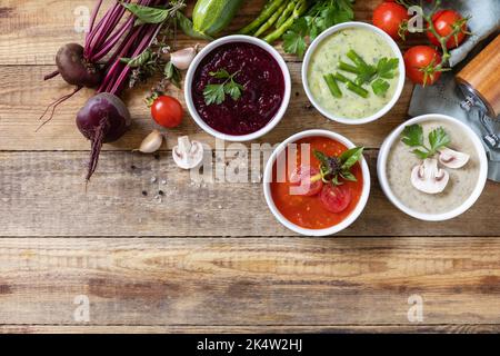 Gesunde Ernährung. Herbstset mit verschiedenen Gemüsesuppen. Vegane heiße Sahnesuppen (Tomaten, Pilze, Rüben, grüne Bohnen) auf rustikalem Holztisch. Ansicht fr Stockfoto