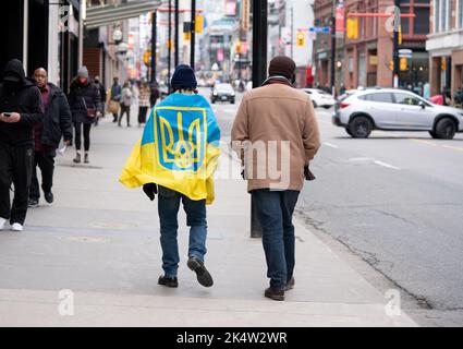 Mann, der 2022 in Toronto, Ontario, Kanada, die Straße entlang ging und eine ukrainische Flagge wekte. Zwei Männer marschieren solidarisch auf der ukrainischen Kundgebung Stockfoto