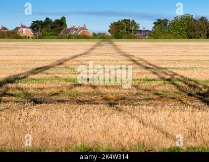 Ich liebe Strommasten; ihre abstrakten, vergilbten Formen finde ich unendlich faszinierend. Hier sehen wir Schatten, die von einem großen Pylon in einem Feld im ländlichen Ra geworfen werden Stockfoto