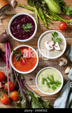 Herbstset mit verschiedenen Gemüsesuppen. Gesunde Ernährung. Vegane heiße Sahnesuppen (Tomaten, Pilze, Rüben, grüne Bohnen) auf rustikalem Holztisch. Ansicht fr Stockfoto