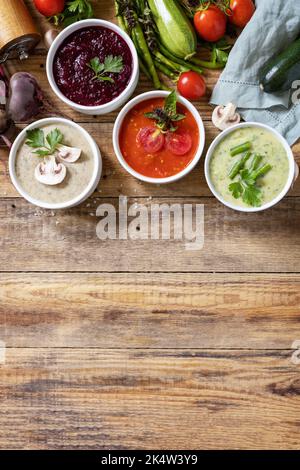 Gesunde Ernährung. Herbstset mit verschiedenen Gemüsesuppen. Vegane heiße Sahnesuppen (Tomaten, Pilze, Rüben, grüne Bohnen) auf rustikalem Holztisch. Ansicht fr Stockfoto