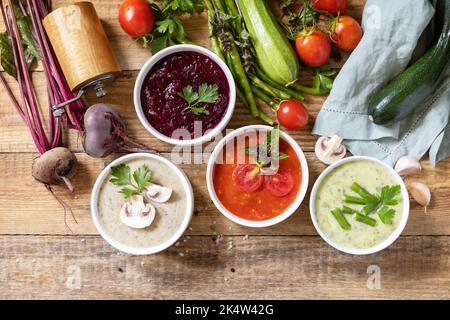 Gesunde Ernährung. Herbstset mit verschiedenen Gemüsesuppen. Vegane heiße Sahnesuppen (Tomaten, Pilze, Rüben, grüne Bohnen) auf rustikalem Holztisch. Ansicht fr Stockfoto