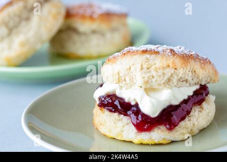 Ein frischer traditioneller englischer hausgemachtes Scone. Der Kuchen wird gespalten und mit Marmelade gefüllt und mit dickem gerinntem Rahm gekrönt. Ein köstlicher Cornish-Cream-Tee. Stockfoto