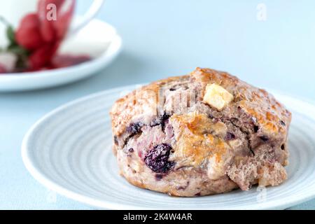 Frisch gebackene Apfel- und Brombeer-Scones, serviert mit einer Tasse Tee in einer porzellanbecher. Gekocht aus einem Rezeptbuch des nationalen Vertrauens Stockfoto