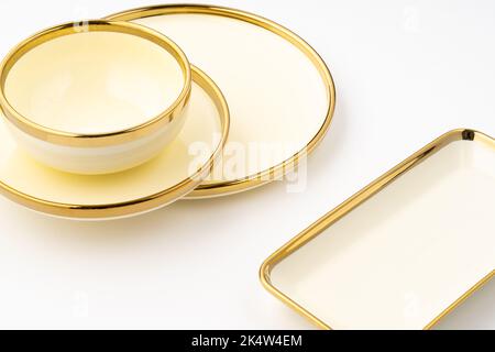 Eine Nahaufnahme von goldenen Luxus-Keramik-Küchenutensilien auf weißem Hintergrund. Stockfoto