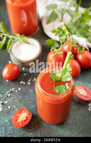 Herbst Vitamin trinken Saft Tomate. Tomatensaft im Glas und frische Tomaten auf einer steinernen Tischplatte. Stockfoto