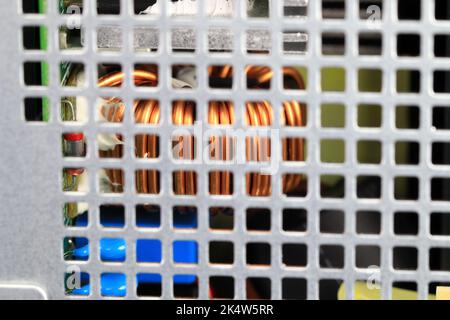 Kupferspule oder Induktivitätsspule auf der Leiterplatte im Netzteil, elektronische Komponenten im Netzteilkasten des Computers. Stockfoto