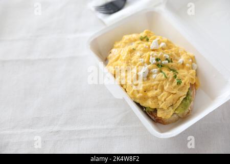 Avocado und Rühreier Toast mit Lieferpaket auf weißem Hintergrund Stockfoto