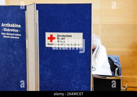 Kiel, Deutschland. 04. Oktober 2022. Ein Arzt sitzt hinter einer Trennwand. Am 4. Oktober 2022 veranstaltete der Blutspendedienst Nord-östlich des Deutschen Roten Kreuzes (DRK) im Kieler Landeshaus eine Blutspendekampagne. Zu diesem Zweck wurde der alte Plenarsaal in ein Blutspendezentrum umgewandelt. Blutspenden helfen, die medizinische Versorgung von Patienten zu sichern, die zum Beispiel im Zuge größerer Operationen oder zur begleitenden Chemotherapie nach Krebs dringend Präparate aus Spenderblut benötigen. Quelle: Frank Molter/dpa/Alamy Live News Stockfoto