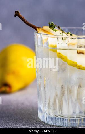 Nahaufnahme eines Birnen-Wodkas und Tonic mit frischer Birne und Thymian Stockfoto