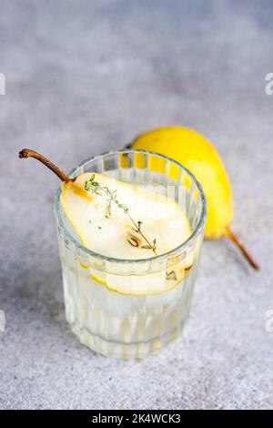 Nahaufnahme eines Birnen-Wodkas und Tonic mit frischer Birne und Thymian Stockfoto