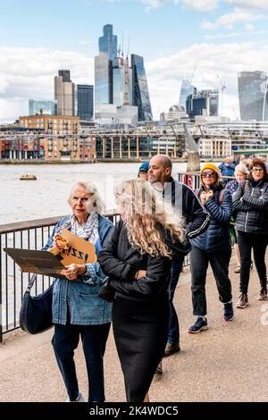 Eine Frau isst Unterwegs eine Pizza, während sie an der Southbank ansteht, um die Queen in der Westminster Hall, London, Großbritannien, im Zustand liegend zu sehen. Stockfoto