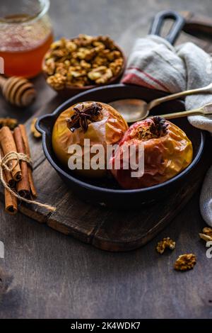 Nahaufnahme von herbstlich gebackenen Äpfeln mit Walnüssen, Honig, Zimt und Sternanise Stockfoto