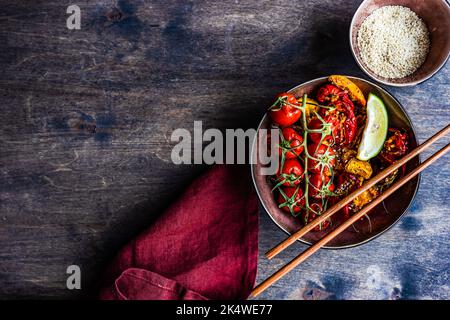 Ansicht von oben auf eine Schüssel mit asiatisch gerösteter Chilischote und Tomaten mit Sesam Stockfoto