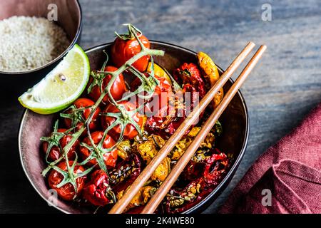 Ansicht von oben auf eine Schüssel mit asiatisch gerösteter Chilischote und Tomaten mit Sesam Stockfoto