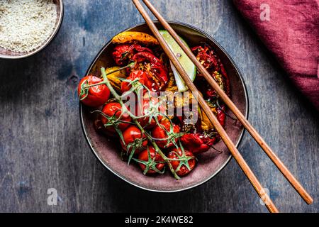 Ansicht von oben auf eine Schüssel mit asiatisch gerösteter Chilischote und Tomaten mit Sesam Stockfoto