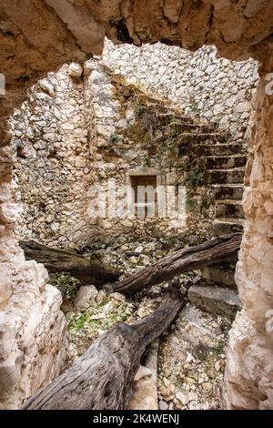 Blick durch die Tür des verfallenden Windmühle Turm mit Steinstufen spiralförmig auf der Innenseite, alten Stein verkommen Turm mit zerbröckelnden Steinstufen. Stockfoto