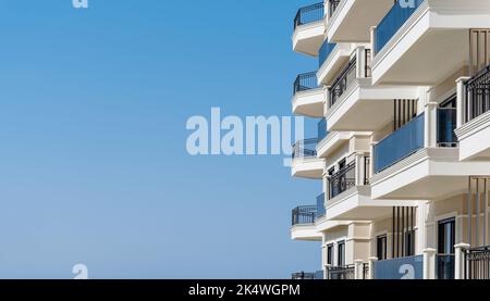 Modernes Apartmentgebäude mit Balkonen, die für Werbetexte isoliert am Himmel liegen. Speicherplatz kopieren. Stockfoto