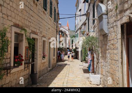 TROGIR, KROATIEN - 23. JUNI 2021: Touristen besuchen die Altstadt von Trogir, Kroatien. Trogir ist eine mittelalterliche Stadt in Dalmatien, die zum UNESCO-Weltkulturerbe zählt Stockfoto