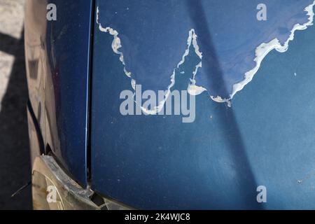 Verwitterte Lackierung der Motorhaube. Abblätternde, sonnenbeschädigte Lackoberfläche in einem 15 Jahre alten kompakten blauen Auto. Stockfoto