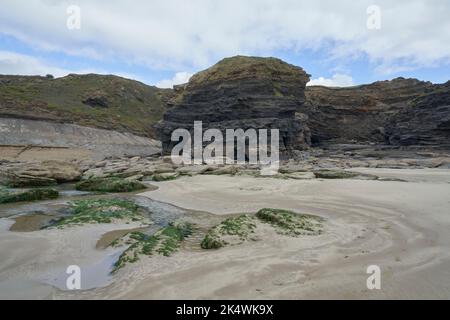 Geologischer Bogen mit an der Spitze verkrusteten Felsen im Vordergrund bei Broadhaven, Pembrokeshire. Stockfoto