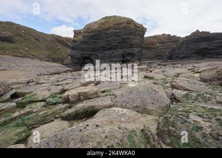 Geologischer Bogen mit an der Spitze verkrusteten Felsen im Vordergrund bei Broadhaven, Pembrokeshire. Stockfoto