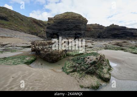 Geologischer Bogen mit an der Spitze verkrusteten Felsen im Vordergrund bei Broadhaven, Pembrokeshire. Stockfoto