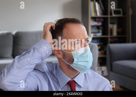 Mann, der versucht, sich zu erinnern, wo er die Autoschlüssel hinlegte. Bärtiger Mann mit Business-Shirt. Erwachsener kaukasischer Mann im Jahr 30s oder 40s. Kratzen des Kopfes nach Stockfoto