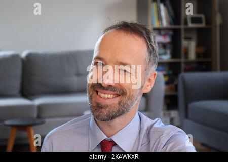 Glücklicher Mann winkend in Richtung Kamera. Bärtiger Mann mit Business-Shirt. Erwachsener kaukasischer Mann im Jahr 30s oder 40s. Stockfoto