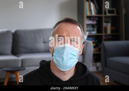 Mann denkt. Konzentrierte Person, die schweres Denken in Gesichtsmaske tut. Bärtiger Mann mit lässigem schwarzem Hoodie. Erwachsener kaukasischer Mann im Jahr 30s oder 40s. Stockfoto