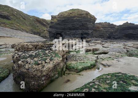 Geologischer Bogen mit an der Spitze verkrusteten Felsen im Vordergrund bei Broadhaven, Pembrokeshire. Stockfoto