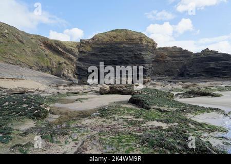 Geologischer Bogen mit an der Spitze verkrusteten Felsen im Vordergrund bei Broadhaven, Pembrokeshire. Stockfoto