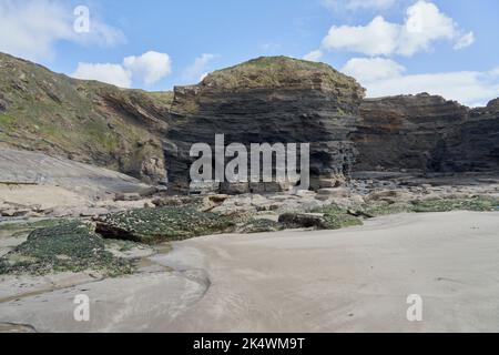 Geologischer Bogen mit an der Spitze verkrusteten Felsen im Vordergrund bei Broadhaven, Pembrokeshire. Stockfoto