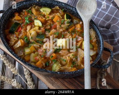 Gemüsesuppe mit Kohl in einem rustikalen Topf auf Holzboden Stockfoto