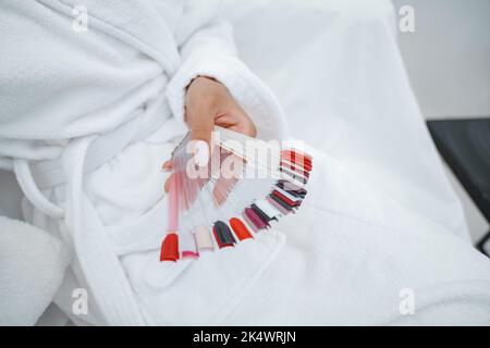 Weibliche Hand hält Farbpalette für Maniküre und Pediküre Nägel im Schönheitssalon Stockfoto