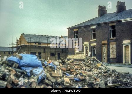 1975 Archivbild des Abrisses alter Reihenhäuser im Nordwesten Englands, daneben Neubau. Vermutlich in Blackburn, Lancashire. Stockfoto